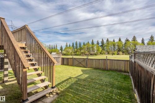 Expansive backyard featuring a wood-plank fence, manicured lawn, and a multi-level wood deck with stairs - 738 Kananaskis Drive, Devon, AB - Outdoor