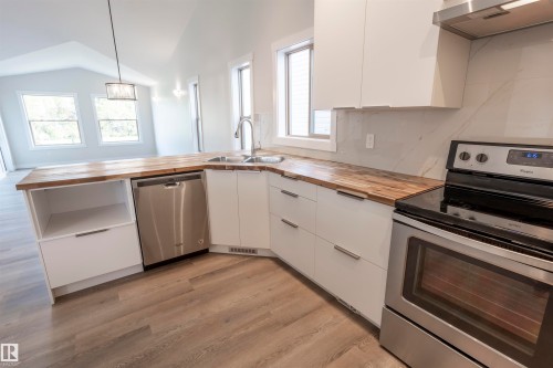 Modern kitchen featuring white cabinetry, wood-finish countertops, and stainless steel appliances - 738 Kananaskis Drive, Devon, AB - Indoor Photo Showing Kitchen With Double Sink