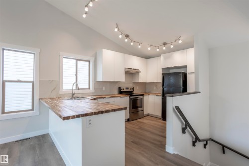 Modern kitchen featuring white cabinetry, wood-finish countertops, stainless steel appliances, and track lighting - 738 Kananaskis Drive, Devon, AB - Indoor Photo Showing Kitchen With Double Sink