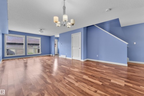 Spacious interior featuring wood-finish flooring, light blue walls, and a contemporary chandelier - 432 Watt Boulevard, Edmonton, AB - Indoor Photo Showing Other Room