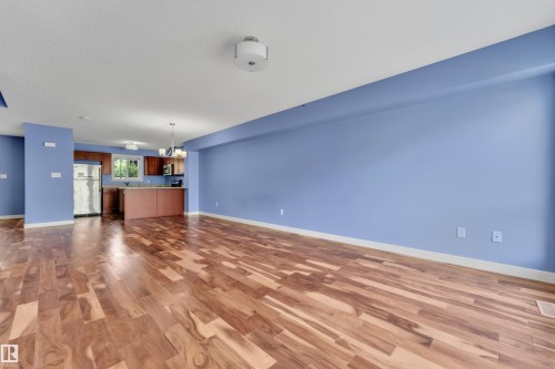 Expansive interior space featuring wide plank wood-finish flooring, light blue wall paint, and a kitchen area with wood cabinetry - 432 Watt Boulevard, Edmonton, AB - Indoor