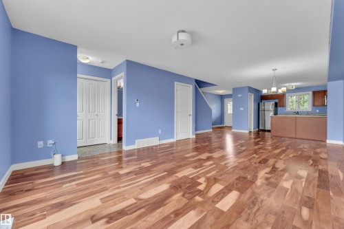 Open-concept living space featuring wood-finish flooring, a kitchen with stainless steel appliances, and a staircase - 432 Watt Boulevard, Edmonton, AB - Indoor