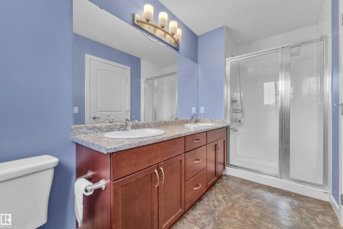 Spacious bathroom featuring a dual vanity with a patterned countertop, a large mirror, and a glass-enclosed shower with white tiled walls - 432 Watt Boulevard, Edmonton, AB - Indoor Photo Showing Bathroom