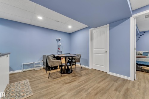 Spacious room featuring wood-finish flooring, light blue walls, a white paneled door, and recessed ceiling lighting - 432 Watt Boulevard, Edmonton, AB - Indoor