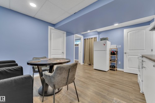 Open-plan area featuring wood-finish flooring, recessed lighting, and a white kitchen cabinet run with a dark countertop - 432 Watt Boulevard, Edmonton, AB - Indoor