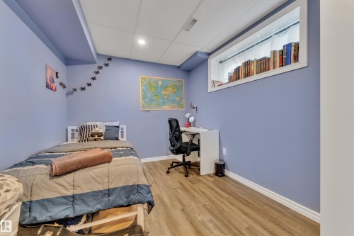 Bedroom featuring wood-finish flooring, drop ceiling, and a large built-in window well with shelving - 432 Watt Boulevard, Edmonton, AB - Indoor