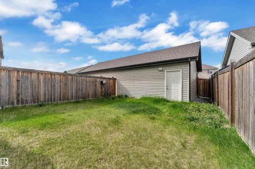 Fenced backyard with a detached garage featuring light gray siding and a side entry door - 432 Watt Boulevard, Edmonton, AB - Outdoor