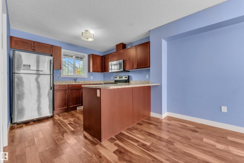 Kitchen featuring rich wood cabinetry, stainless steel appliances, and a central island with a granite-style countertop - 432 Watt Boulevard, Edmonton, AB - Indoor Photo Showing Kitchen