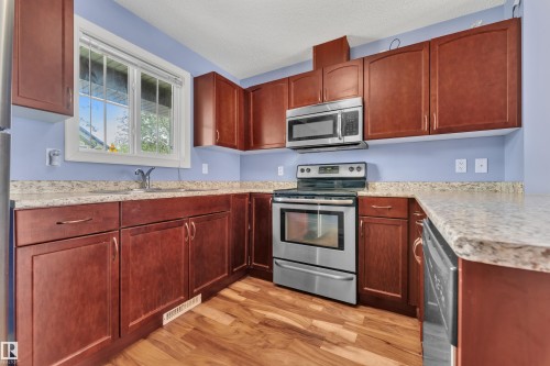 Kitchen featuring wood-finish flooring, light-toned countertops, and rich wood-toned cabinetry - 432 Watt Boulevard, Edmonton, AB - Indoor Photo Showing Kitchen With Stainless Steel Kitchen With Double Sink