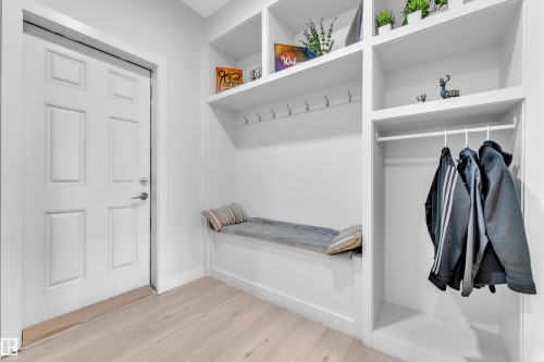 Entryway featuring wood-finish flooring, a paneled door, built-in shelving, integrated coat hooks, and a built-in bench - 1118 Goldfinch Crescent, Edmonton, AB - Indoor With Storage