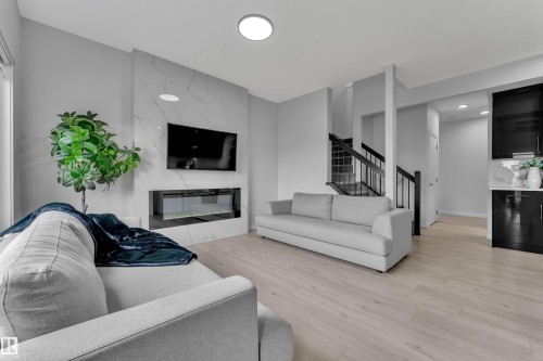 Living area featuring a floor-to-ceiling accent wall with a built-in electric fireplace and light wood-finish flooring - 1118 Goldfinch Crescent, Edmonton, AB - Indoor Photo Showing Living Room With Fireplace