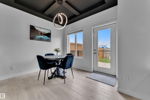 Dining area featuring a coffered ceiling with a modern chandelier and wood-finish flooring - 1118 Goldfinch Crescent, Edmonton, AB - Indoor Photo Showing Dining Room
