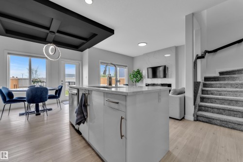 Spacious kitchen island with light-toned countertop, wood-finish flooring, and a contemporary ceiling feature - 1118 Goldfinch Crescent, Edmonton, AB - Indoor Photo Showing Kitchen