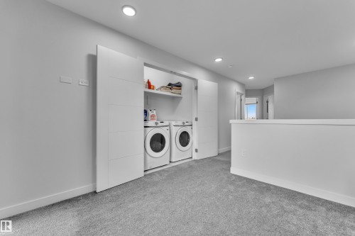 Dedicated laundry area featuring front-loading appliances, white shelving, and modern sliding barn doors - 1118 Goldfinch Crescent, Edmonton, AB - Indoor Photo Showing Laundry Room