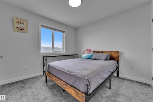 Bright room featuring a large window, plush gray carpeting, white walls, and a modern ceiling light fixture - 1118 Goldfinch Crescent, Edmonton, AB - Indoor Photo Showing Bedroom