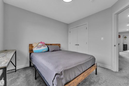 Carpeted room with light grey walls, featuring a double-door closet with black hardware - 1118 Goldfinch Crescent, Edmonton, AB - Indoor Photo Showing Bedroom
