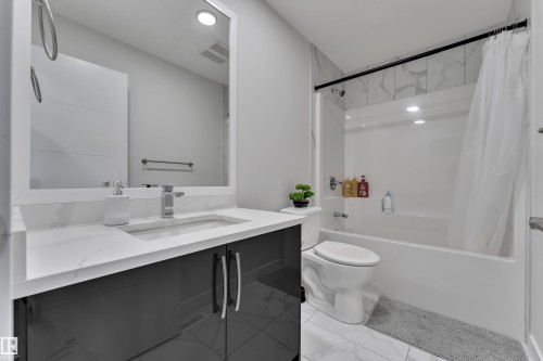 Contemporary bathroom featuring a dark gray vanity with a white countertop, an undermount sink, and chrome fixtures - 1118 Goldfinch Crescent, Edmonton, AB - Indoor Photo Showing Bathroom