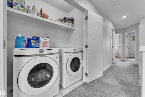 Dedicated laundry area featuring a front-load washer and dryer, an overhead shelf, and white walls - 1118 Goldfinch Crescent, Edmonton, AB - Indoor Photo Showing Laundry Room