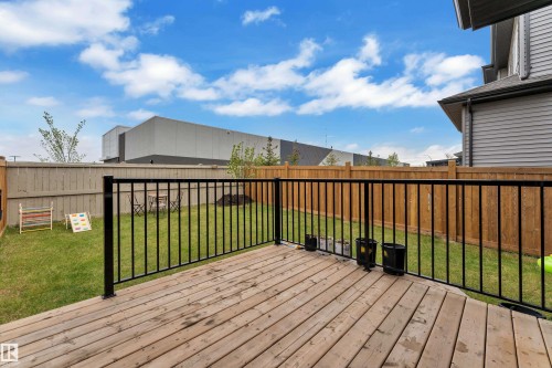 Spacious wooden deck with black metal railings overlooking a fenced backyard featuring a grassy area - 1118 Goldfinch Crescent, Edmonton, AB - Outdoor With Deck Patio Veranda With Exterior