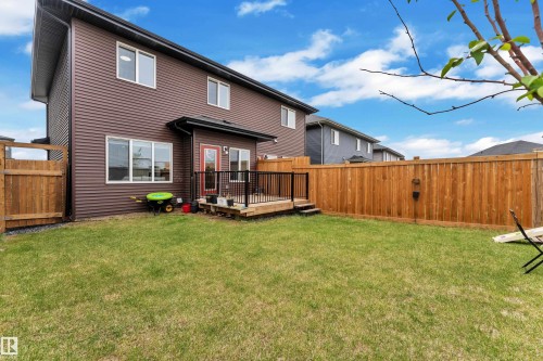 Expansive backyard featuring a manicured lawn, full wood fencing, and a raised wood deck with black metal railings - 1118 Goldfinch Crescent, Edmonton, AB - Outdoor With Deck Patio Veranda