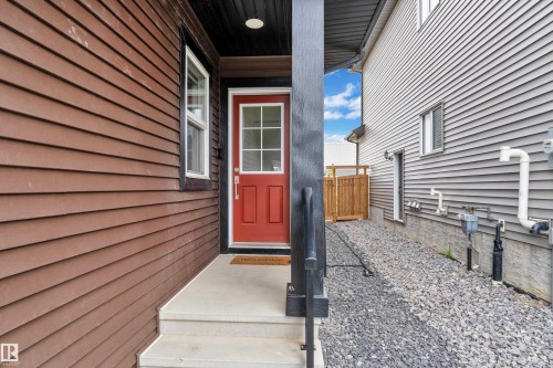Red entry door with grid-pane glass and a concrete stoop - 1118 Goldfinch Crescent, Edmonton, AB - Outdoor With Exterior
