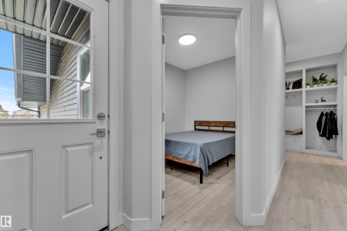 Entryway featuring a white paneled door with windowpanes, light wood-finish flooring, a built-in shelving unit, and a built-in bench - 1118 Goldfinch Crescent, Edmonton, AB - Indoor Photo Showing Other Room