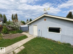 Detached garage with light blue horizontal siding, white trim, and a pedestrian door - 