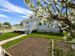 Rear exterior featuring light blue siding and a spacious wooden deck with railings - 