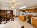 Kitchen featuring wood-finish cabinetry, light-toned countertops, and a central island - 4005 55 Avenue, Whitecourt, AB  - Indoor Photo Showing Kitchen With Double Sink 