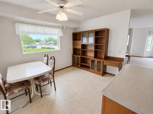 Dining area featuring neutral tile flooring and a built-in wood-finish storage unit with glass-front cabinets and an integrated desk - 4005 55 Avenue, Whitecourt, AB - Indoor