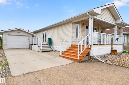 Exterior featuring light-colored siding, a covered front porch with white railings, and wood-finish steps - 1727 Jubilee Loop, Sherwood Park, AB - Outdoor With Deck Patio Veranda
