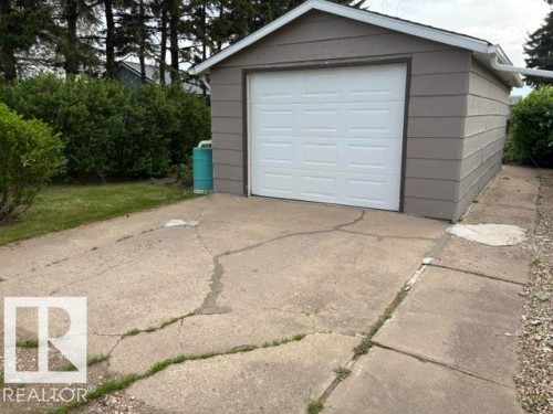 Detached garage with horizontal siding, a white panel garage door, and a white gutter system - 5454 46 Street, Vegreville, AB - Outdoor With Exterior