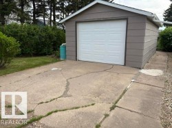 Detached garage with horizontal siding, a white panel garage door, and a white gutter system - 