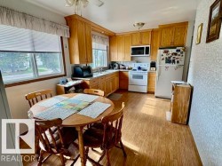 Kitchen with wood-finish flooring, wood cabinetry, and white appliances - 