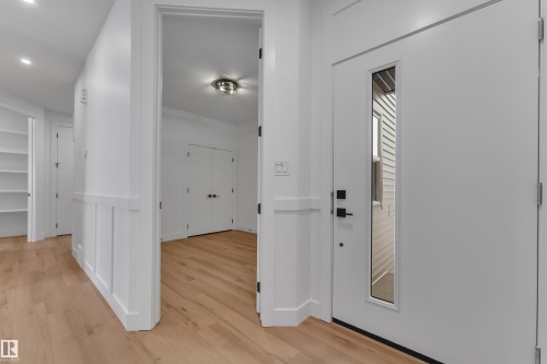 Entryway featuring a white door with vertical glass insert, matte black hardware, and light wood-finish flooring - 2027 156 Avenue, Edmonton, AB - Indoor Photo Showing Other Room