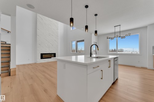 Modern kitchen island with a white countertop, undermount sink, and black gooseneck faucet - 2027 156 Avenue, Edmonton, AB - Indoor Photo Showing Kitchen With Upgraded Kitchen