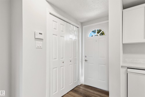 Entryway featuring a paneled door with an arched transom window, wood-finish flooring, and bi-fold closet doors - 707 Clareview Road, Edmonton, AB - Indoor Photo Showing Other Room