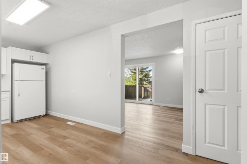 Kitchenette area featuring wood-finish flooring, white cabinetry, and a top-freezer refrigerator - 707 Clareview Road, Edmonton, AB - Indoor