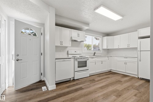 Kitchen featuring white cabinetry, white appliances, wood-finish flooring, and a white countertop - 707 Clareview Road, Edmonton, AB - Indoor Photo Showing Kitchen