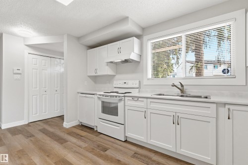 Kitchen featuring white cabinetry, a double basin stainless steel sink, and wood-finish flooring - 707 Clareview Road, Edmonton, AB - Indoor Photo Showing Kitchen With Double Sink