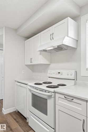 Kitchen workspace featuring white cabinetry, a built-in range, a dishwasher, and light-toned countertops - 707 Clareview Road, Edmonton, AB - Indoor Photo Showing Kitchen