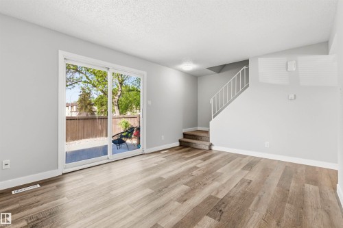 Spacious living area featuring wood-finish flooring, light gray walls, and a white ceiling - 707 Clareview Road, Edmonton, AB - Indoor