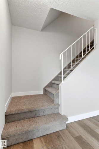 Carpeted staircase featuring white balusters and a wood-finish flooring landing - 707 Clareview Road, Edmonton, AB - Indoor Photo Showing Other Room