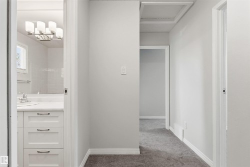 Hallway with gray carpet flooring and white trim, featuring a bathroom entrance with a vanity, sink, and an overhead light fixture - 707 Clareview Road, Edmonton, AB - Indoor Photo Showing Other Room