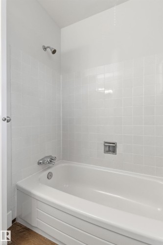 White tiled shower surround with a built-in tub, chrome shower head, and chrome tub fixtures - 707 Clareview Road, Edmonton, AB - Indoor Photo Showing Bathroom