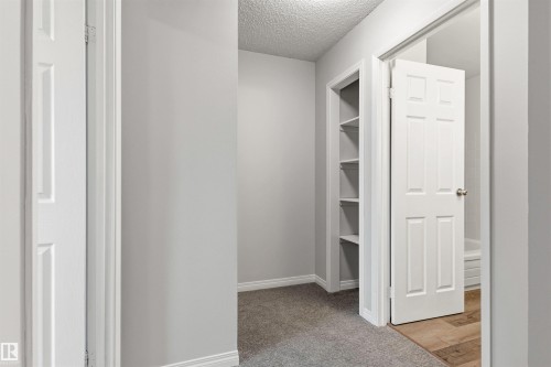 Hallway featuring built-in shelving, gray carpet, white baseboards, and a white paneled door - 707 Clareview Road, Edmonton, AB - Indoor Photo Showing Other Room