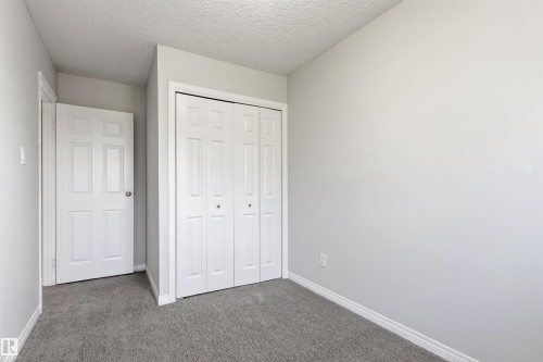 Neutral gray wall finishes, textured ceiling, light gray carpeting, bi-fold closet doors, and white trim - 707 Clareview Road, Edmonton, AB - Indoor