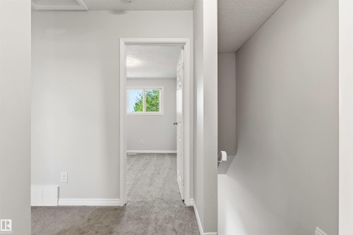 Interior doorway with white trim opens to a room featuring a window with green foliage outside - 707 Clareview Road, Edmonton, AB - Indoor Photo Showing Other Room