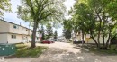 Multi-unit residential complex featuring light-colored siding exteriors, multiple entry doors, and a paved common area - 707 Clareview Road, Edmonton, AB  - Outdoor 