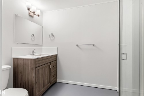 Bathroom featuring a wood-finish vanity with an integrated sink, a large mirror, and a frameless glass shower enclosure - 707 Clareview Road, Edmonton, AB - Indoor Photo Showing Bathroom